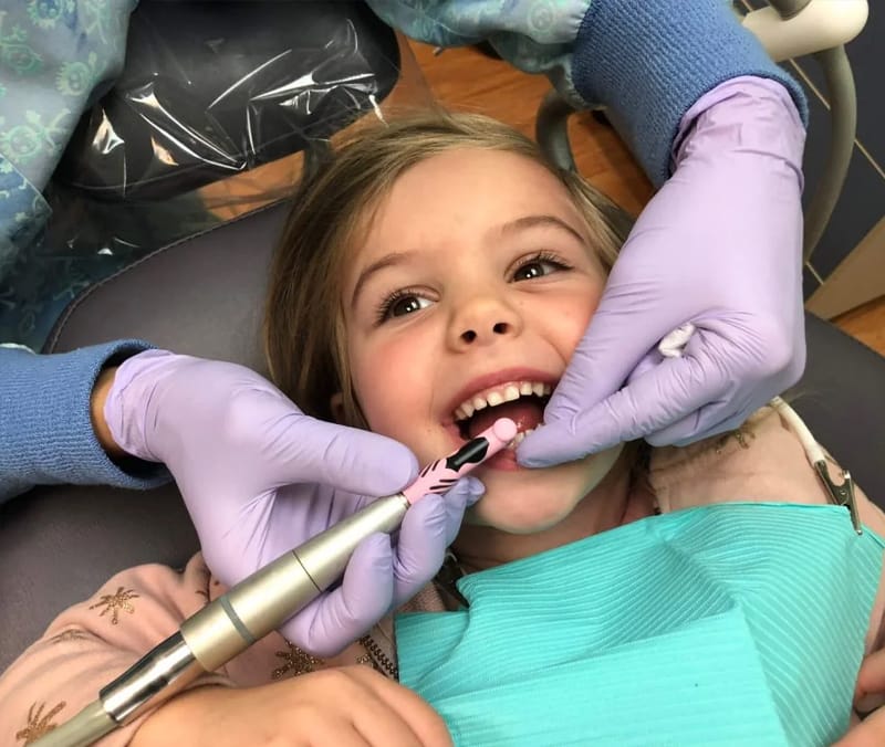 Criança sorrindo durante o atendimento na cadeira do dentista