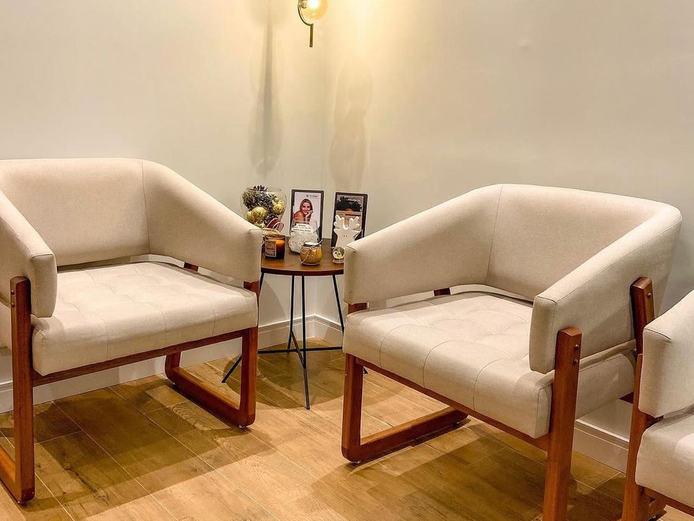 Sala de espera da unidade Santos da GS Odontologia, com poltronas, estação de café e painel de madeira